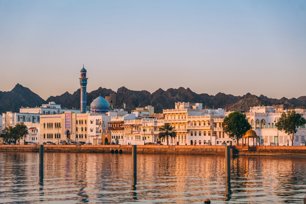 Luxury Muscat Oman yacht charter sunrise waterfront city skyline with mosque and mountains
