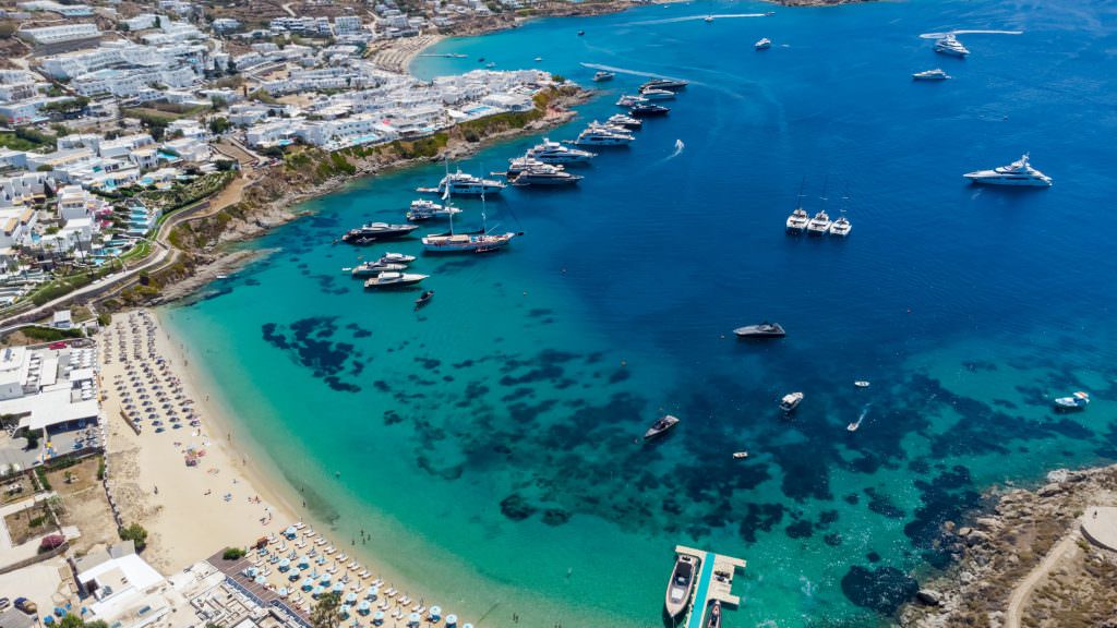 Mykonos yacht charter Aerial view of Mykonos beach with luxury yachts and turquoise water Greek island Mediterranean