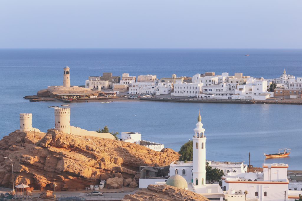 Luxury Oman yacht charter Muscat coastline with lighthouse fort and traditional old town
