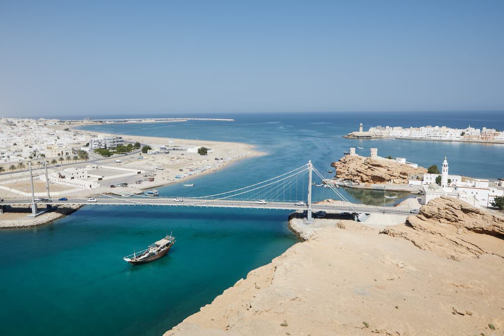 Luxury Oman yacht charter Sur coastline with bridge turquoise sea and coastal city