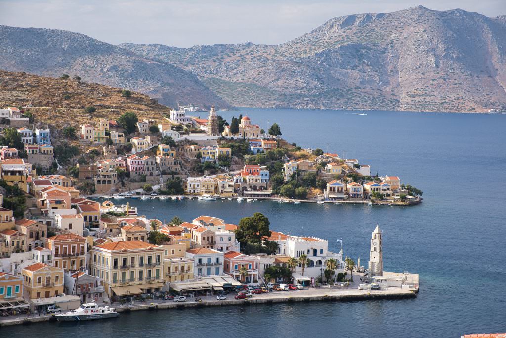Symi yacht charter Gialos harbour panorama with colorful neoclassical houses Greece