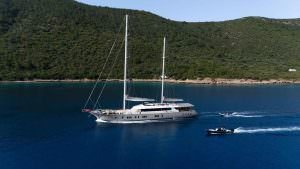 De Love motor sailer exterior aerial view cruising along Turkish coastline, luxury yacht charter experience with tender boats and scenic nature