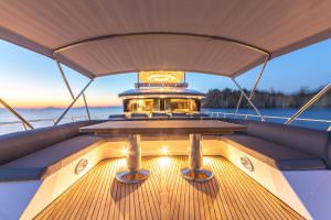 Floki luxury yacht charter bow deck dining area at sunset with ambient lighting and sea view