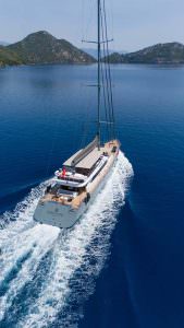 North Wind motor sailer aerial cruising view, luxury yacht navigating calm waters with scenic coastal backdrop and premium charter experience