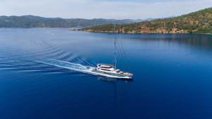 North Wind motor sailer aerial wide view, luxury yacht cruising through calm blue waters surrounded by scenic coastline and natural beauty