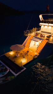 North Wind motor sailer aft deck at night, luxury yacht illuminated with warm lighting, elegant outdoor seating and sea reflections under night sky