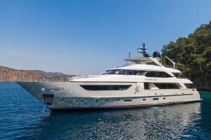 Luxury yacht Takara One side view cruising near coastline with clear blue sea